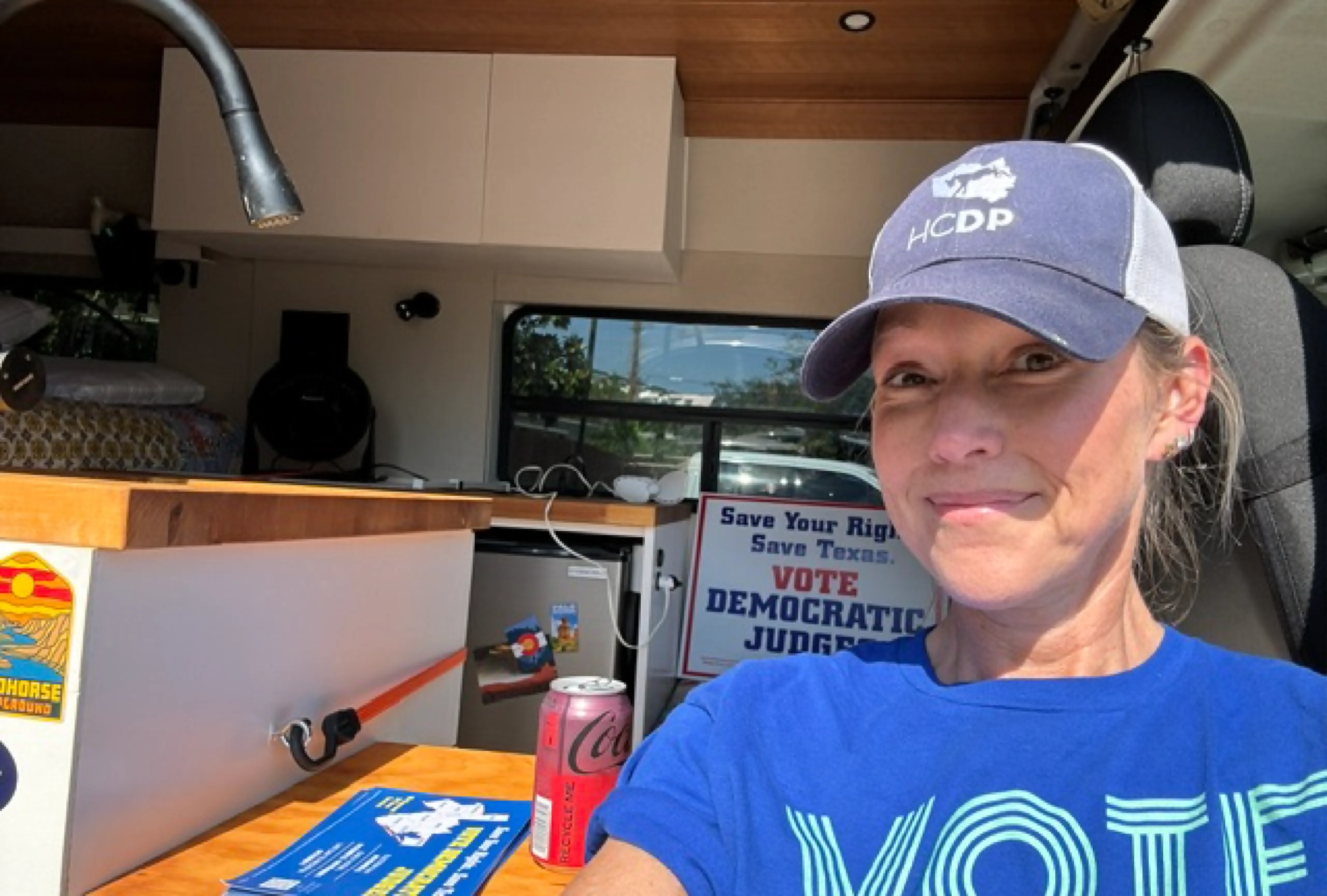 Former Justice Julie Countiss wearing a "Save Your Rights, Vote Democratic" hat and blue shirt,
